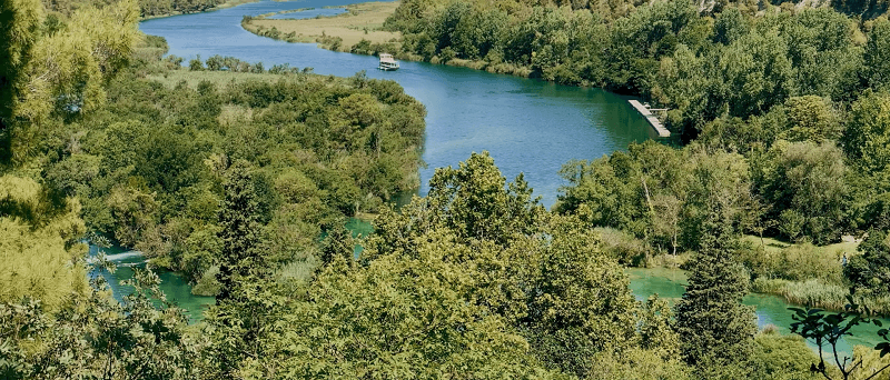 Krka river with a boat traveling up it.