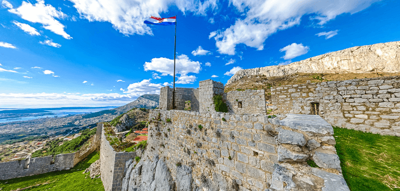 A picture of a Croatian flag on top of the Fortress of Klis.